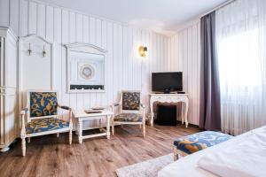 ein Wohnzimmer mit 2 Stühlen und einem TV in der Unterkunft Central Hotel am Königshof in Viernheim