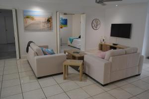 a living room with two couches and a flat screen tv at Oasis on Nautilus in Port Douglas