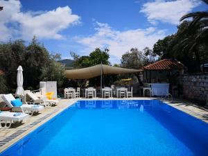 a large swimming pool with chairs and an umbrella at Anofli Suites in Skopelos Town