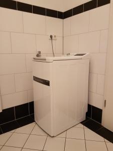 a small white refrigerator in a white tiled bathroom at City Lodge Apartment in Leipzig