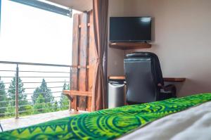 a bedroom with a bed and a television and a balcony at Tahiti Hills Lodge in Punaauia