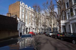 a street with cars parked in front of buildings at Linden Gardens in London