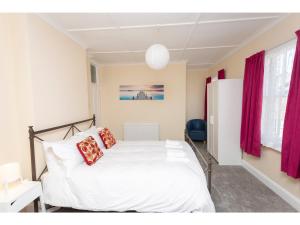 a bedroom with a white bed with red curtains at Sandown Villa Holiday Home in Deal