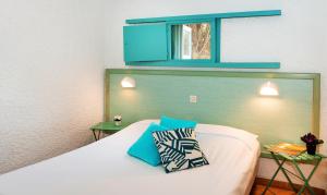 een slaapkamer met een bed en een blauw raam bij Village Vacances de Ramatuelle - Les sentier des pins in Saint-Tropez