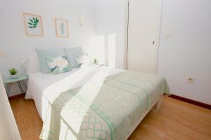 a white bedroom with a bed with a green and white blanket at Sant Miquel Homes - Turismo de interior in Palma de Mallorca +19 photos