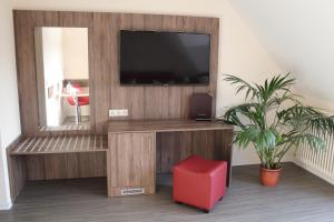 ein Wohnzimmer mit einem TV und einem roten Stuhl in der Unterkunft Hotel Knorre in Meißen