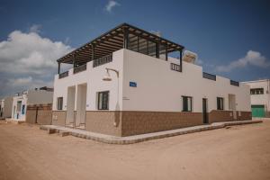 a large white building on a dirt road at La Pardela Experience Apartamentos in Caleta de Sebo
