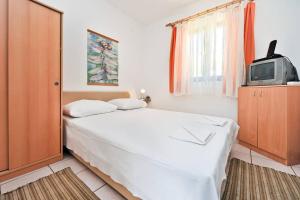 a bedroom with a white bed and a tv at Sunny Bi-Pi Apartment in Pag