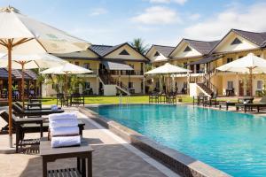 a resort pool with lounge chairs and umbrellas at Sansan Resort in Vang Vieng
