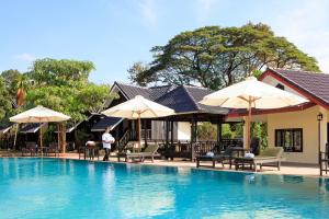 a pool at a resort with chairs and umbrellas at Sansan Resort in Vang Vieng