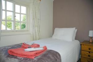 a bedroom with a bed with a red blanket and a window at 1 Hope Cottage in Spilsby