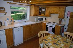 eine Küche mit Holzschränken, einem Tisch und einem Fenster in der Unterkunft 1 Hope Cottage in Spilsby