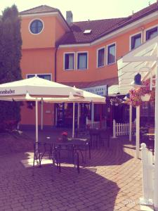 a patio with tables and umbrellas in front of a building at ates Hotel Lampertheim in Lampertheim