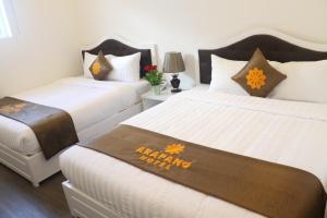 una camera con 2 letti con lenzuola bianche e cuscini marroni di Arapang Hotel 2 a Da Lat