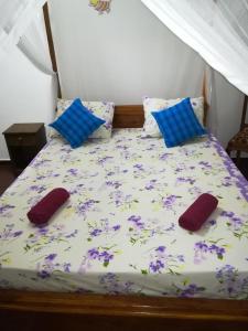 łóżko z dwoma poduszkami i fioletowymi kwiatami w obiekcie Lasindu Guest w mieście Ahangama