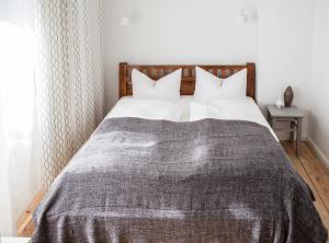 ein Bett mit einer grauen Decke und weißen Kissen in der Unterkunft Pension Absolut Berlin in Berlin