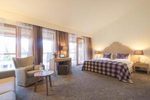 ein Schlafzimmer mit einem Bett, einem Sofa und einem Stuhl in der Unterkunft Hotel Exquisit in Oberstdorf