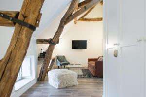 Habitación con vigas de madera y sala de estar con sofá. en La Maison Deveney Mars en Puligny-Montrachet