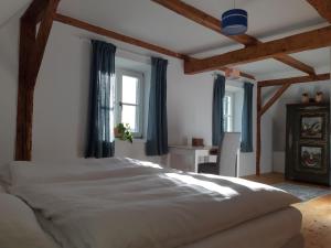 Schlafzimmer mit einem großen weißen Bett und blauen Vorhängen in der Unterkunft Erzherzog-Johann Ferienhaus mit besonderem Flair in Stainz