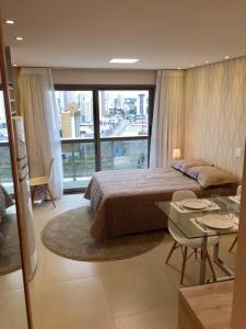 1 dormitorio con cama, mesa y ventana grande en Estudio moderno com linda vista para a Serra en Curitiba