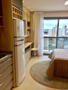 a kitchen with a refrigerator and a bed and a window at Estudio moderno com linda vista para a Serra in Curitiba