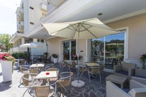 a patio with tables and chairs and an umbrella at Hotel Savana in Rimini