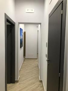 korytarz z białymi ścianami, czarnymi drzwiami i drewnianą podłogą w obiekcie Guesthouse Ughetti 21 w Katanii