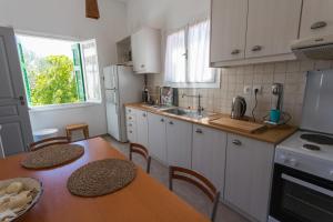 a kitchen with white cabinets and a table with chairs at Irini's house in Spetses +36 photos