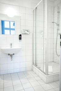 a white bathroom with a sink and a shower at Pension Peters – Das andere Hotel in Berlin