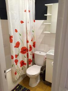 a bathroom with a toilet with a flower shower curtain at Traditional fisherman cottage in Yport