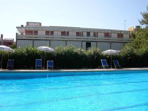 three chairs and umbrellas next to a swimming pool at Appartamenti Marina del Forte in Marina di Bibbona