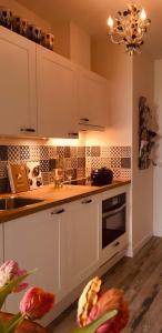 a kitchen with white cabinets and a stove at Maison la Tulipe in Zoutelande