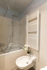 a white bathroom with a sink and a bath tub at Tergesteo Palace Suite in Trieste