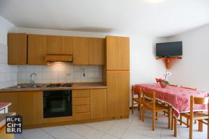 a kitchen with wooden cabinets and a table and a television at CASA MIFEL -- APP. GERANIO in Folgaria