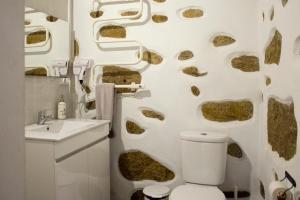 a bathroom with a toilet and a wall with rocks at CoutoRural in Vila Nova de Gaia +65 photos