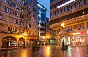 an empty city street at night with buildings at Duerming Longoria Plaza Hotel in Oviedo