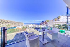 a balcony with a table and chairs and a view of the ocean at Cala Clara Beach Apartment by Sealand Villas in Cala de Sant Vicenc