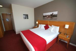 a bedroom with a large bed with a red blanket at Kingstown Hotel by Greene King Inns in Hull +20 photos