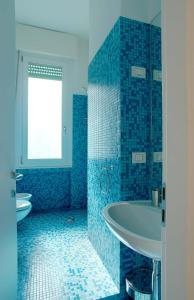 ミラノにあるミラン アパートメント レンタルの青いタイル張りのバスルーム(シンク2台、バスタブ付)