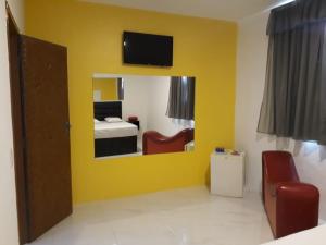 a room with a yellow wall with a bed and a mirror at Motel Sky (Adults Only) in Salvador