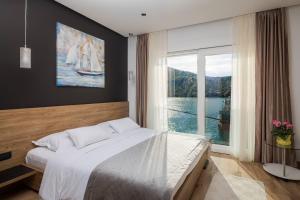 sypialnia z dużym łóżkiem i dużym oknem w obiekcie Beachfront Luxury Villa w mieście Vinišće
