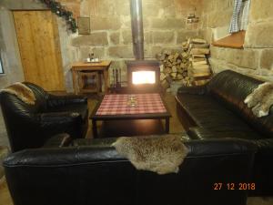 a living room with two leather couches and a wood stove at Chalupa-statek Arkáda in Božanov