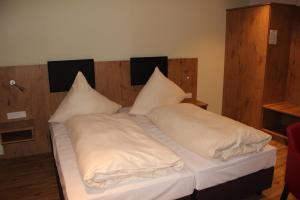 ein Bett mit weißer Bettwäsche und Kissen darauf in der Unterkunft Gasthof Zur Post in Schwabhausen bei Dachau