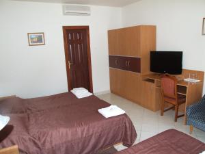 a hotel room with two beds and a desk and a television at Rákóczi Panzió in Sárospatak