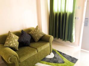 a green couch in a living room with a green curtain at Calliandras Apartment Complex in Kingstown