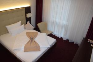 a hotel room with a bed with a tie on it at Hotel Jungstil in Darmstadt