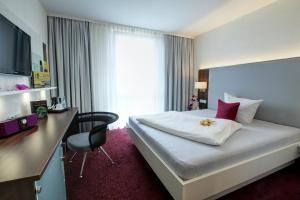ダルムシュタットにあるHotel Jungstilの大きなベッドとデスクが備わるホテルルームです。