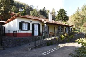une petite maison blanche avec un mur en pierre dans l'établissement Casas de Pedra, à Camacha