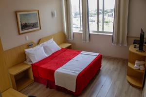 a bedroom with a red and white bed with a window at Airam Brasília Hotel in Brasília