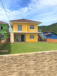 a yellow house with a fence in front of it at Pousadajn in Florianópolis